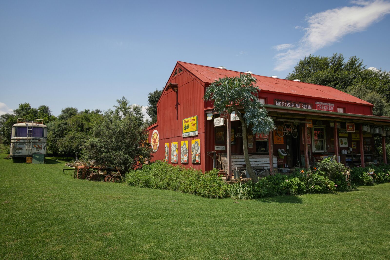 A vintage farmhouse with vibrant red roof and rustic decor set in a lush, green landscape.
